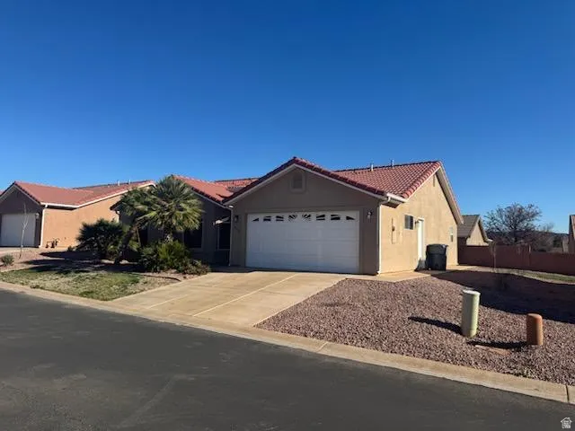 Ranch-style house featuring stucco siding, driveway, a garage, and a tiled roof