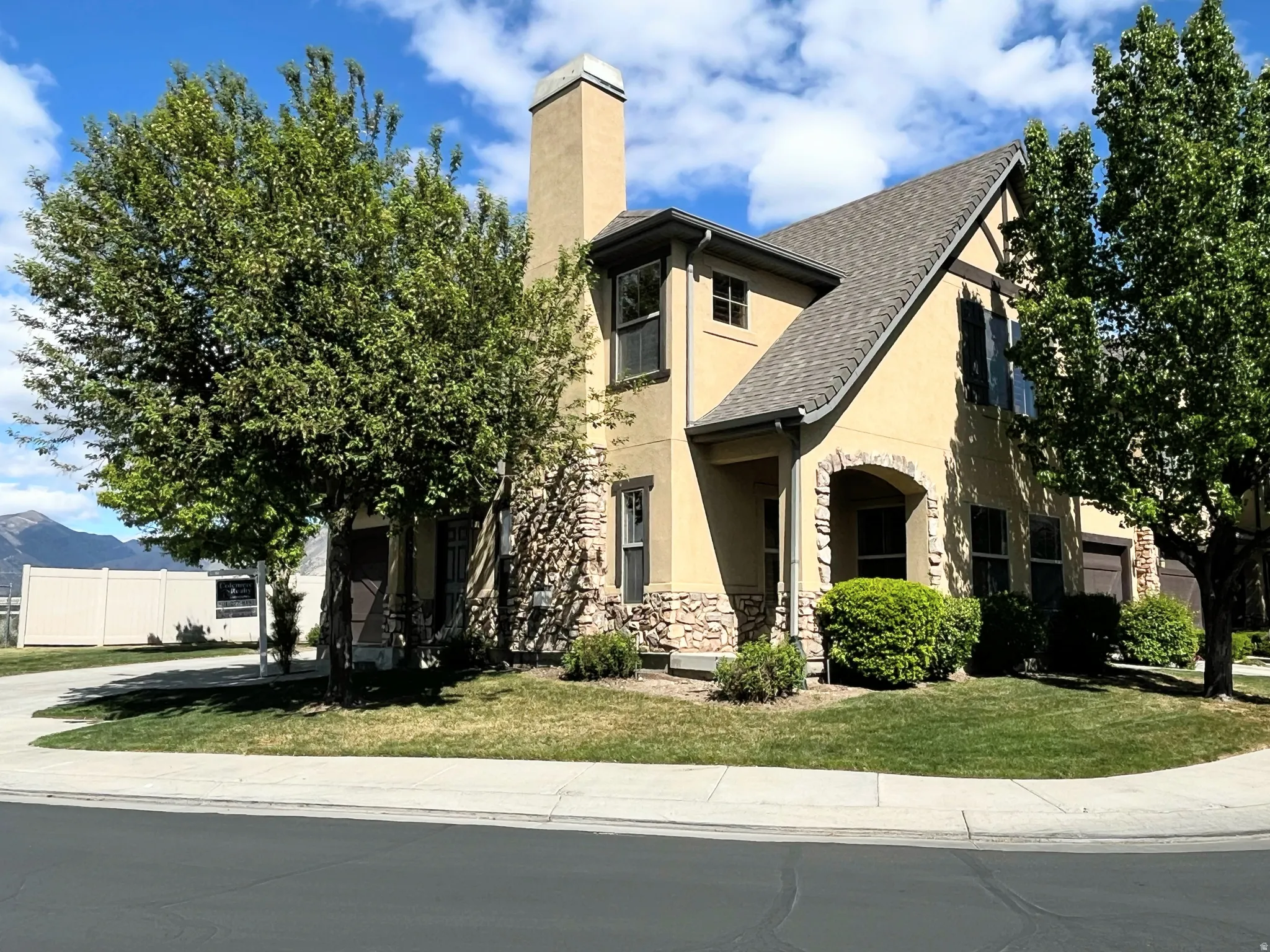 View of front of house with stucco siding, a front lawn, a chimney, stone siding, and a mountain view