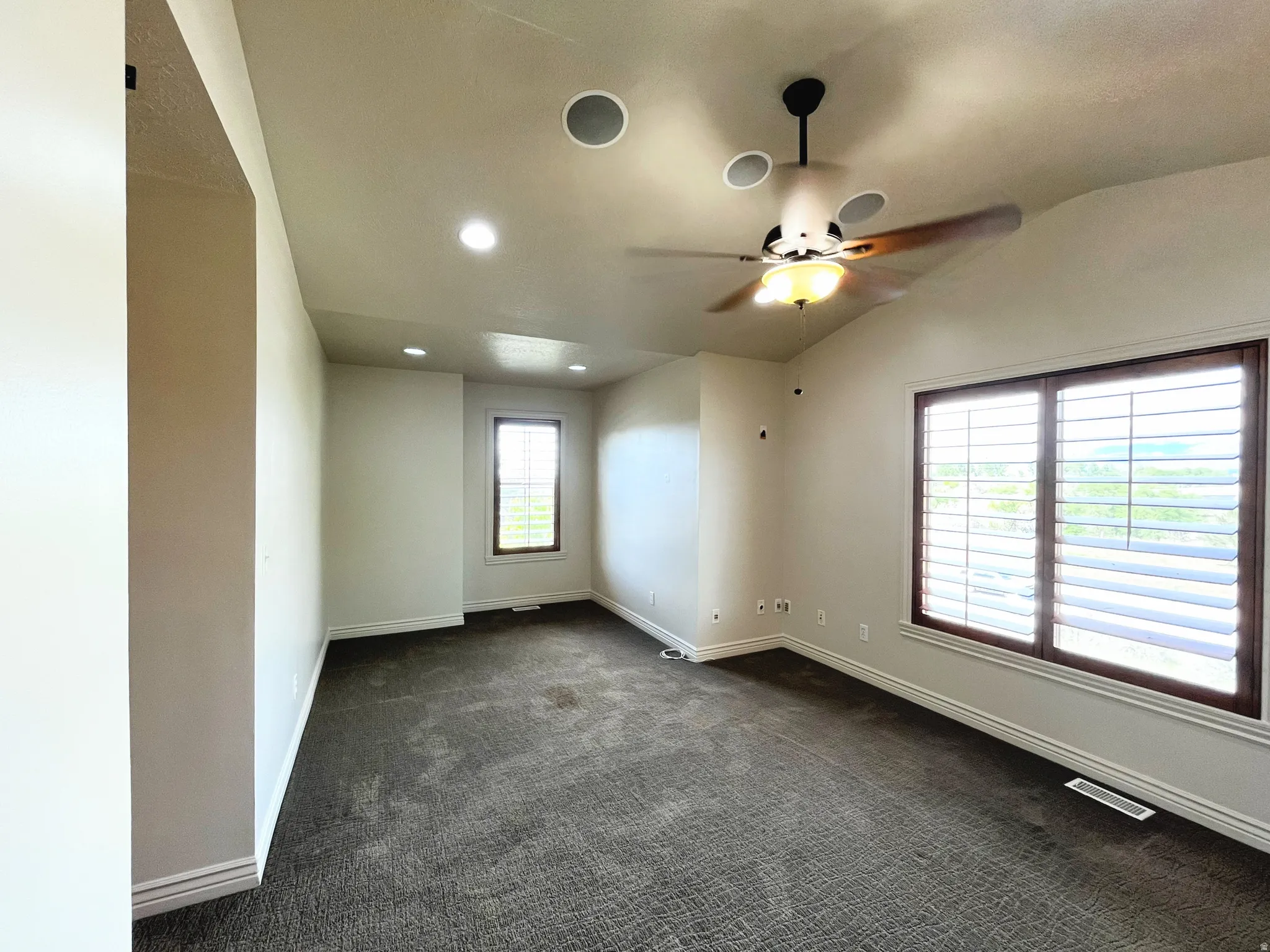 Unfurnished room featuring dark colored carpet, a ceiling fan, vaulted ceiling, and recessed lighting