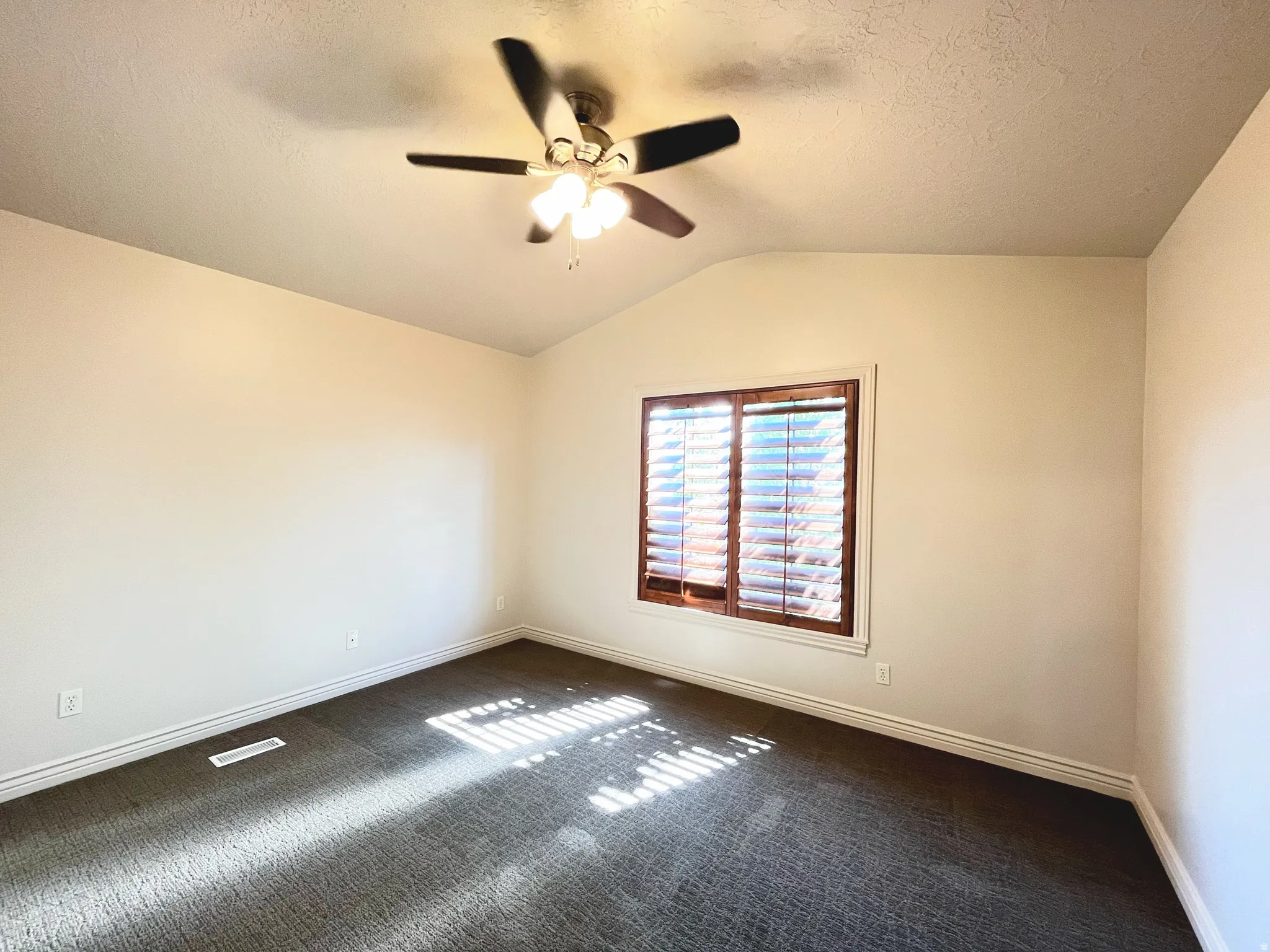 Unfurnished room featuring dark carpet and ceiling fan