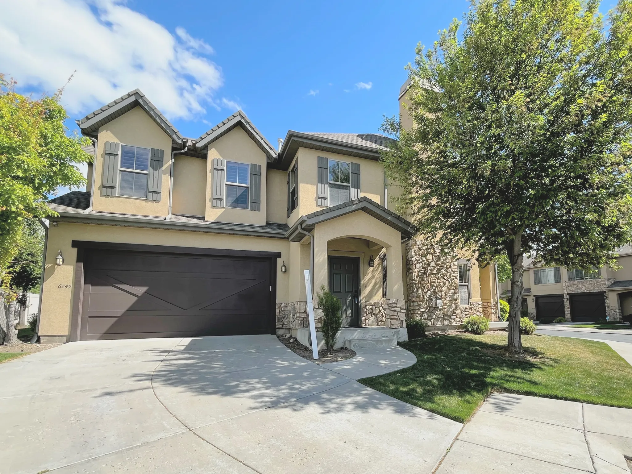 View of front of property with concrete driveway, stucco siding, a garage, stone siding, and a front yard