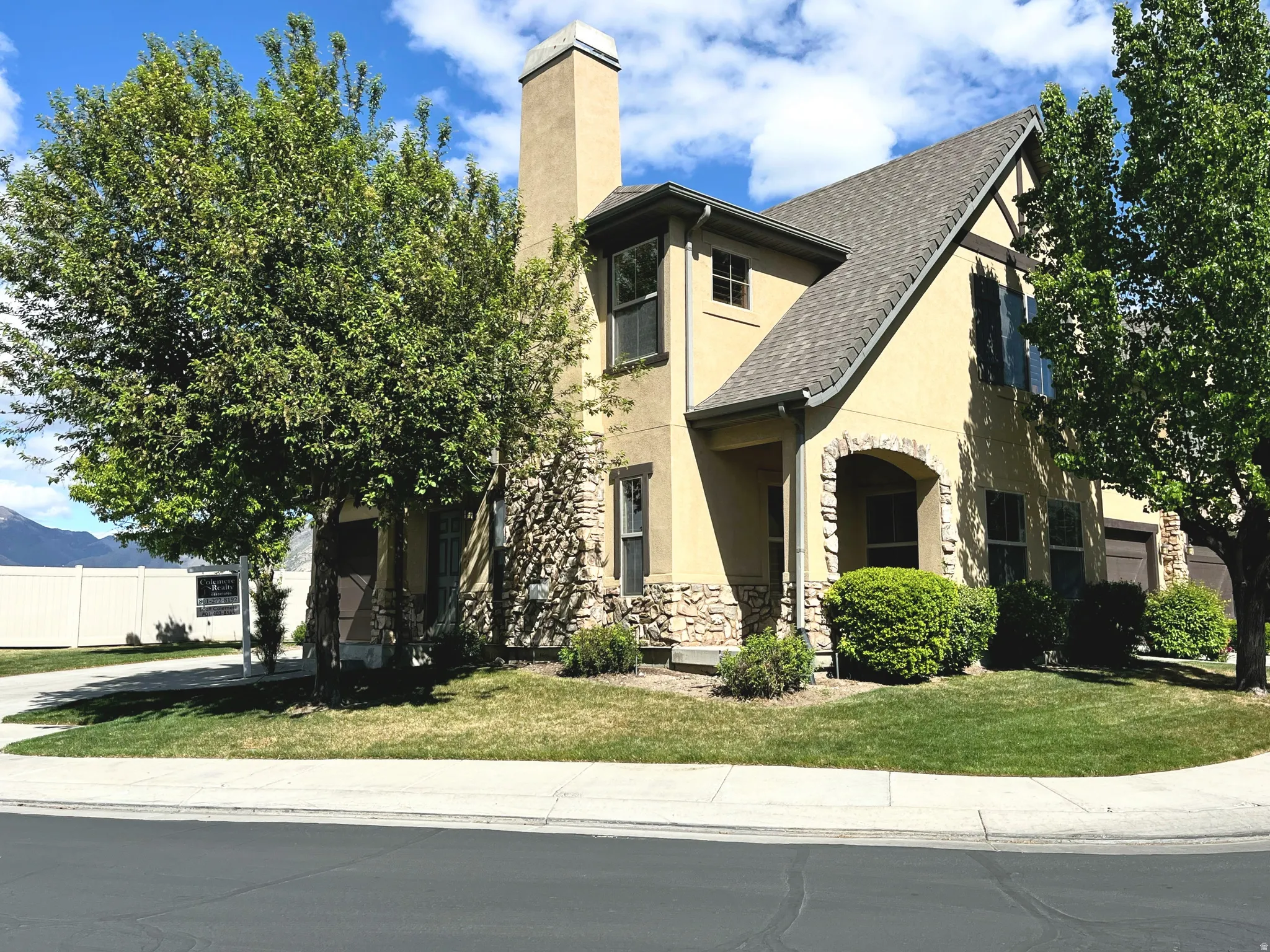 View of front of house featuring stucco siding, a chimney, and stone siding