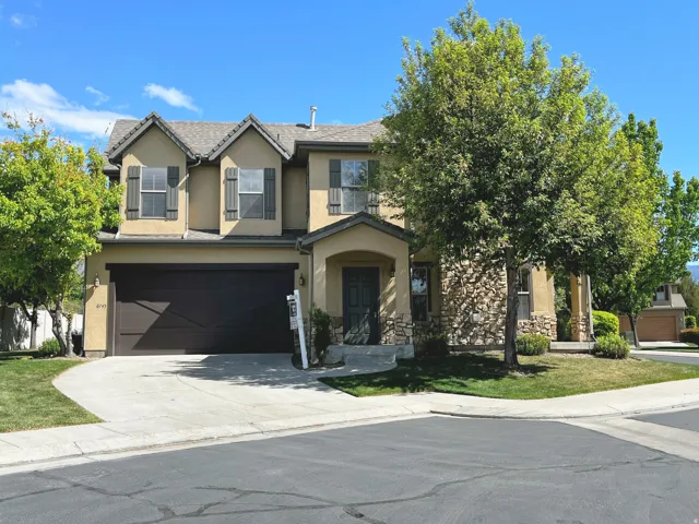 Traditional-style home with a garage, driveway, stucco siding, and stone siding