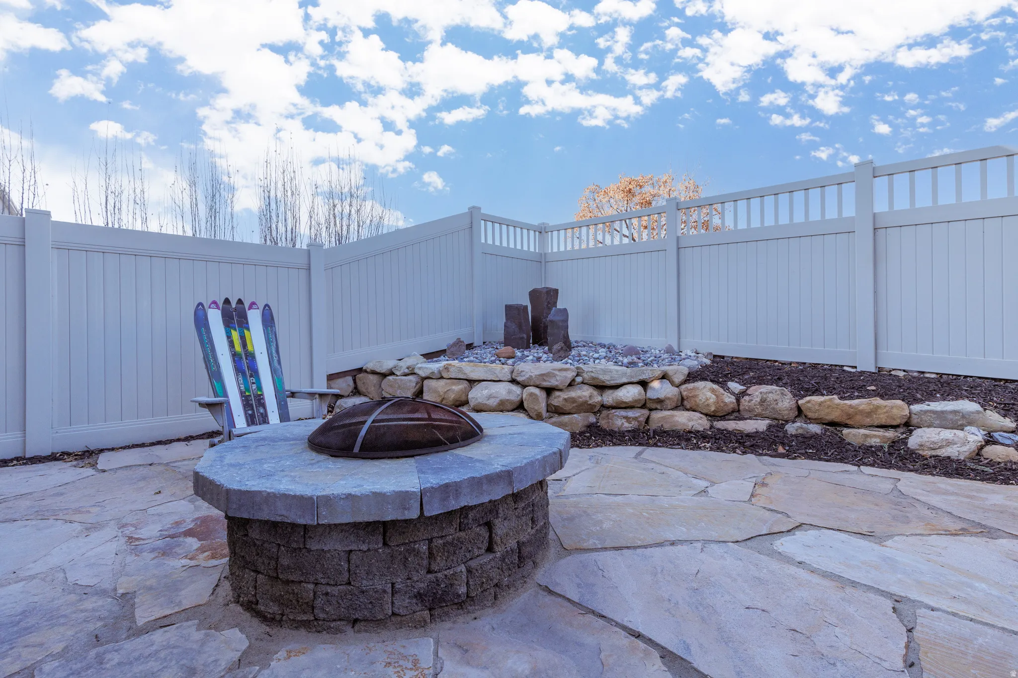 Fenced backyard with flagstone patio, water feature and outdoor fire pit.