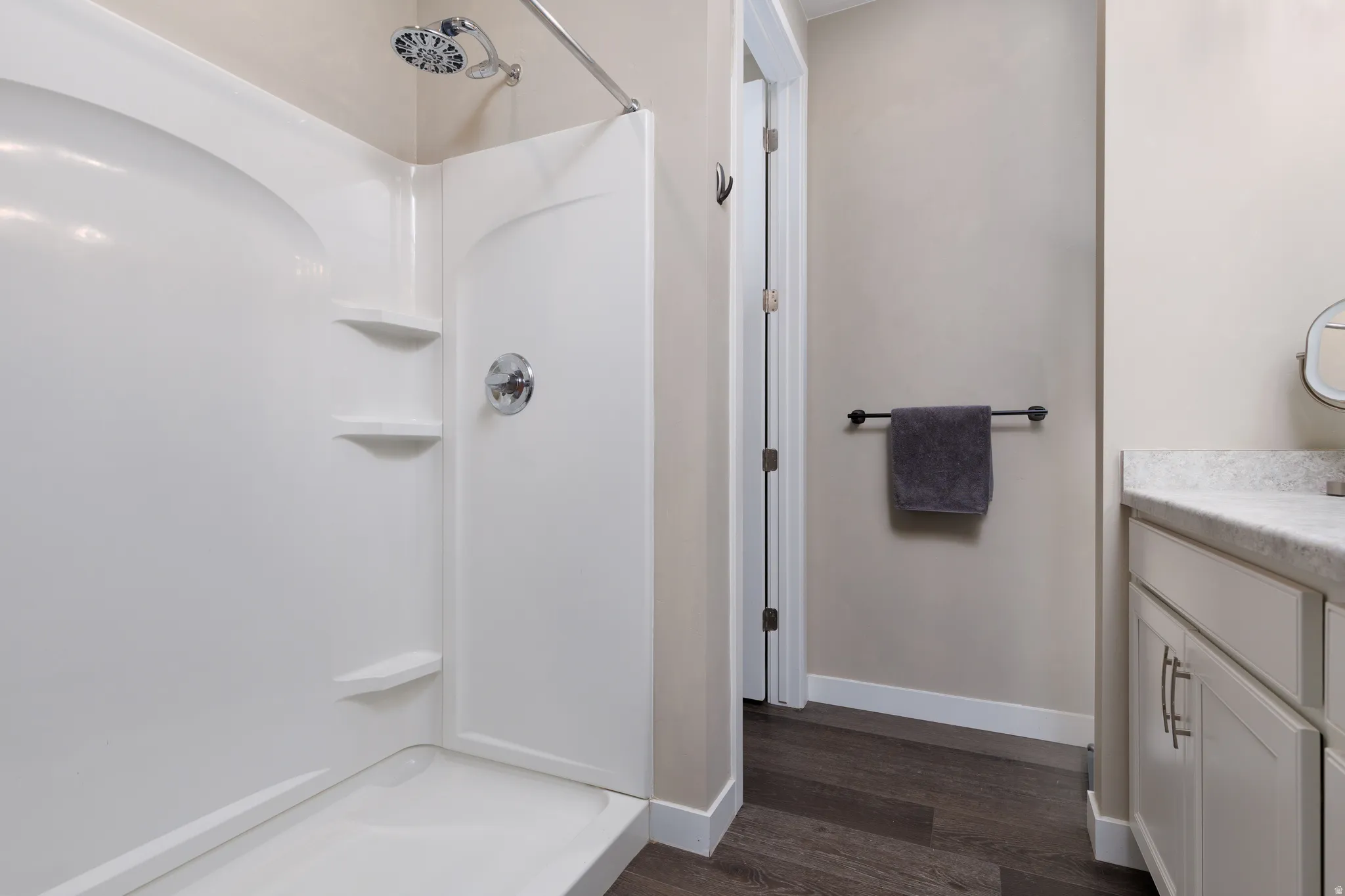 Full bathroom featuring water closet, vanity, walk in shower, linen closet and dark wood finished floors.