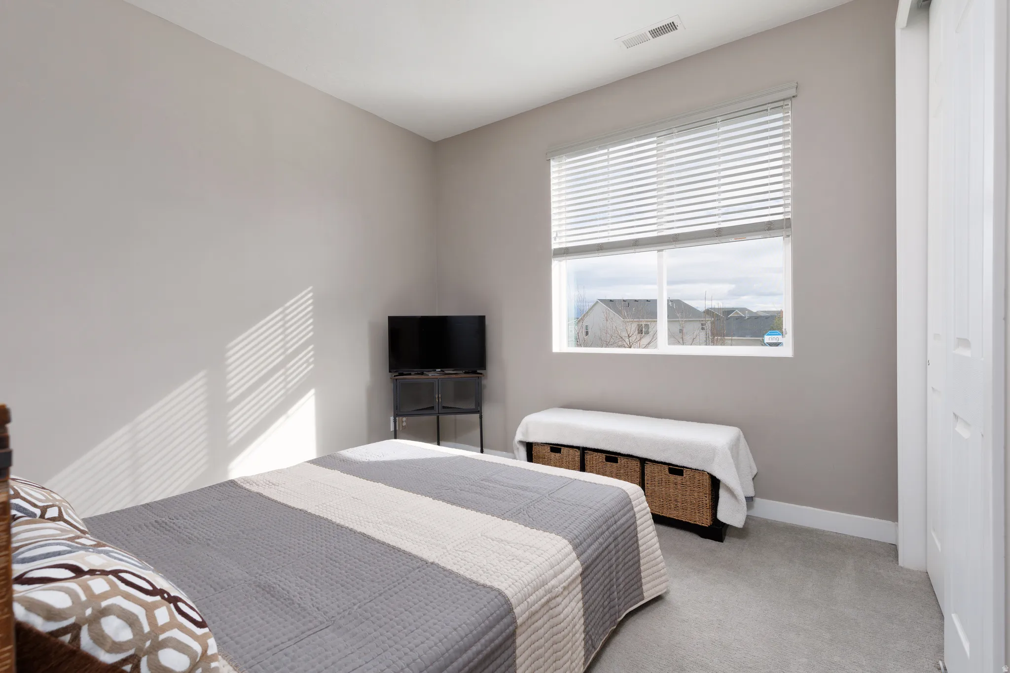 Bedroom featuring carpeted floor, custom blinds and sun drenched window with view of park.