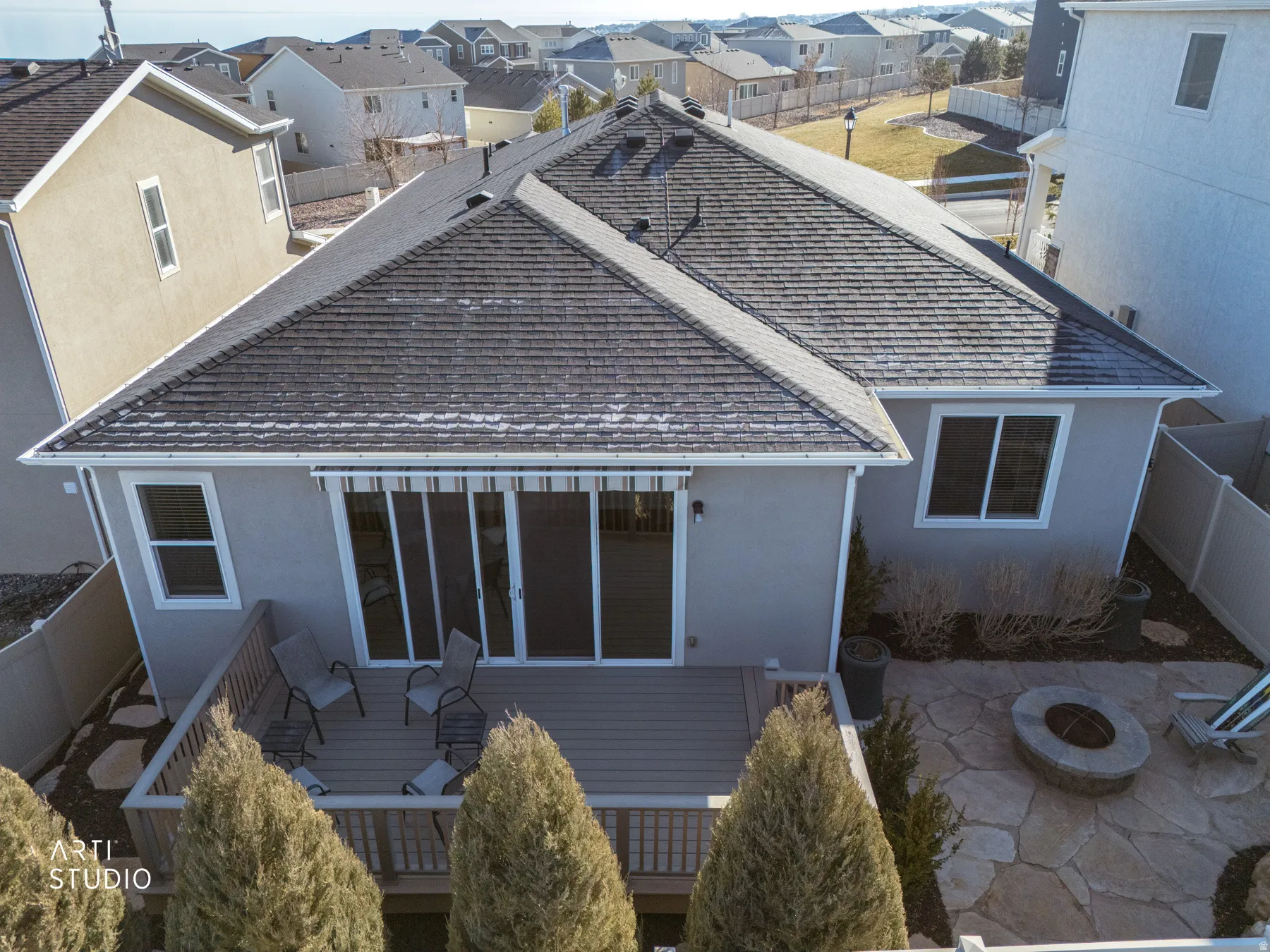 Back of home featuring custom landscaping, fenced backyard, roof with dish, fire pit, and residential view with glimpse of park