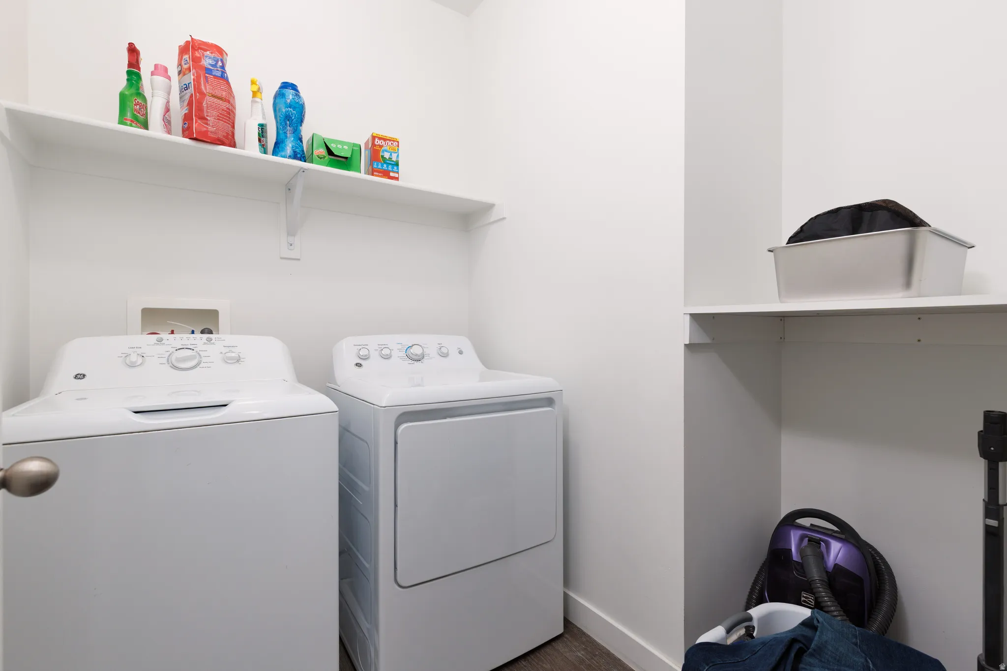 Laundry room with clothes washer and dryer, dual  shelving and dark wood finished floor.
