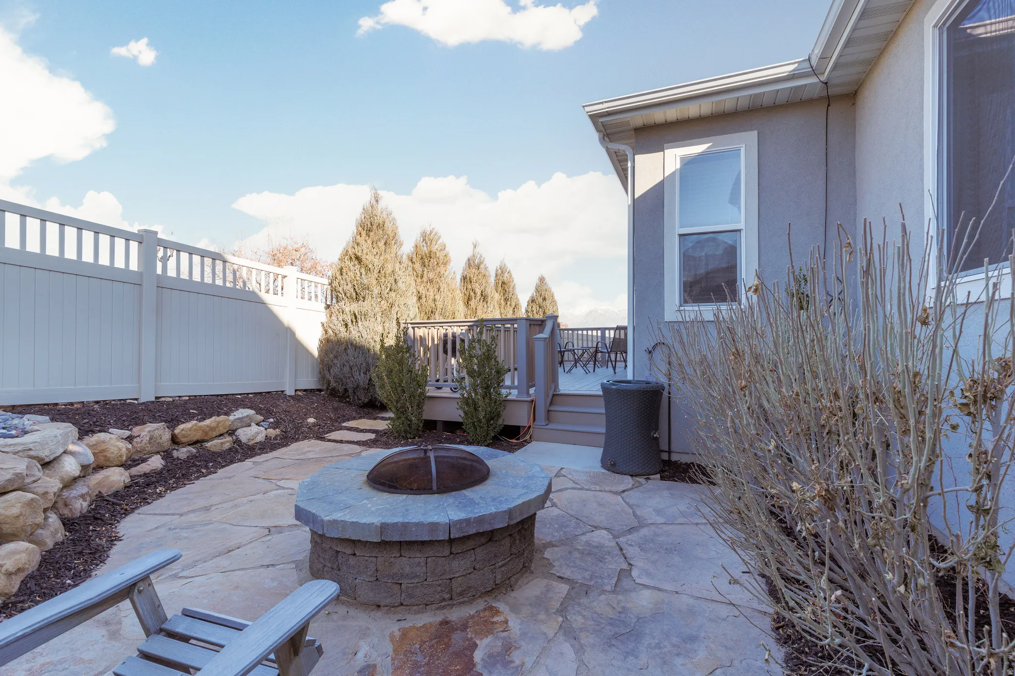 Fenced backyard with outdoor fire pit, Trex deck,  patio area and custom landscaping.