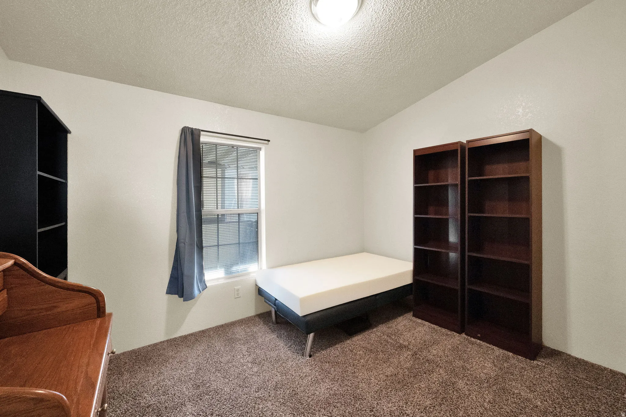 Bedroom with carpet, a textured ceiling, and vaulted ceiling