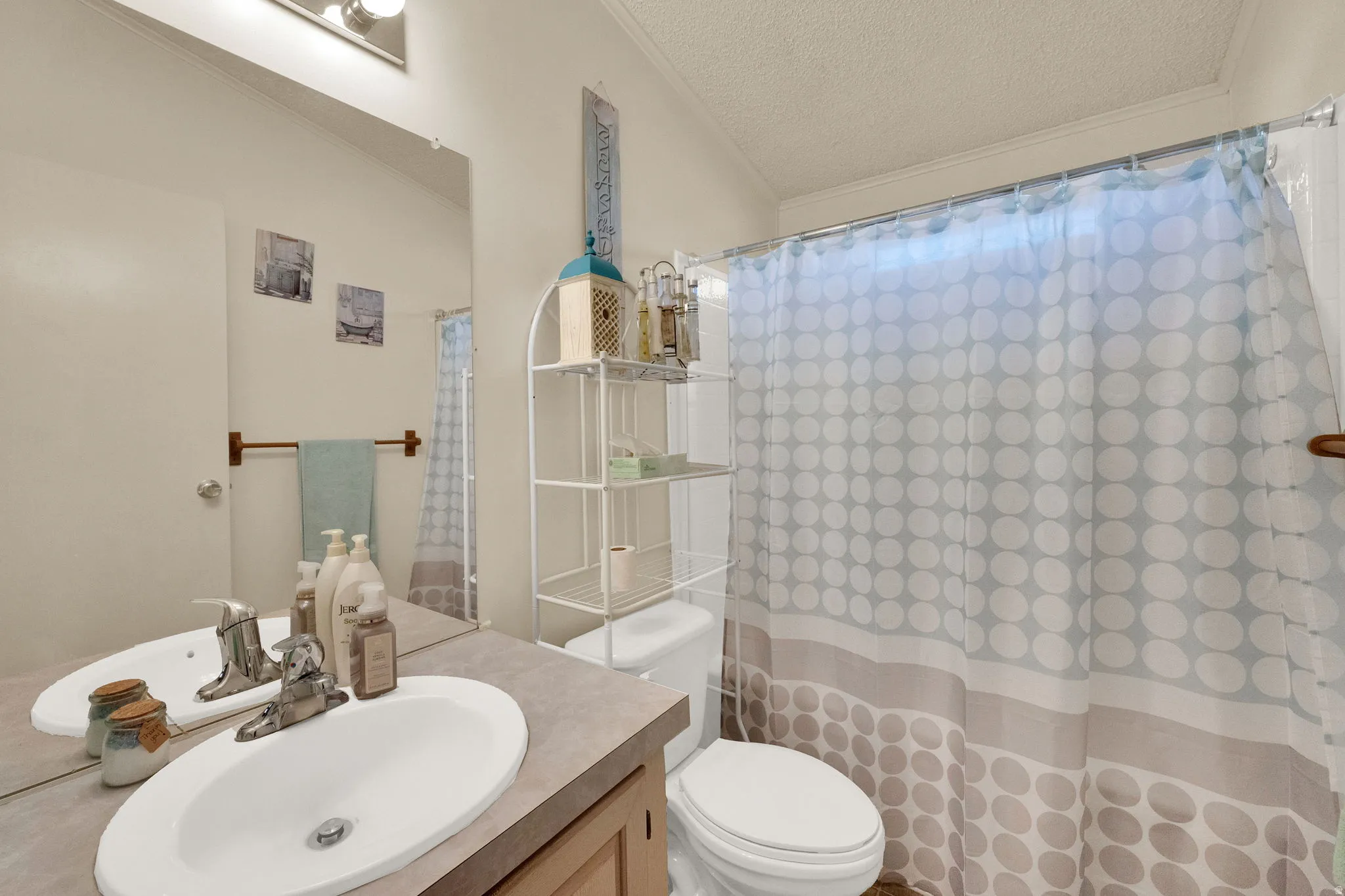 Full bathroom featuring vanity, a textured ceiling, a shower with curtain, and crown molding