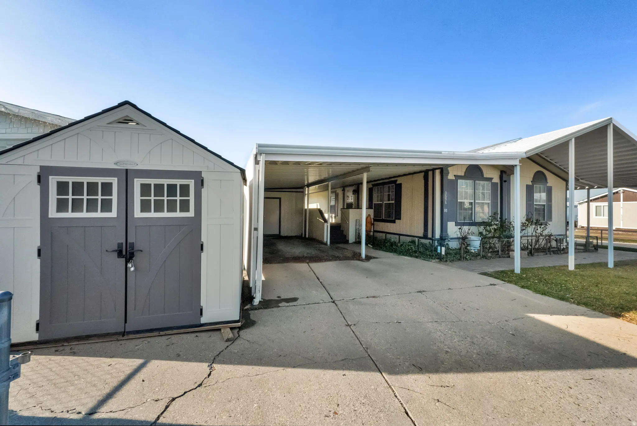 View of front facade with a storage shed, a carport, and driveway
