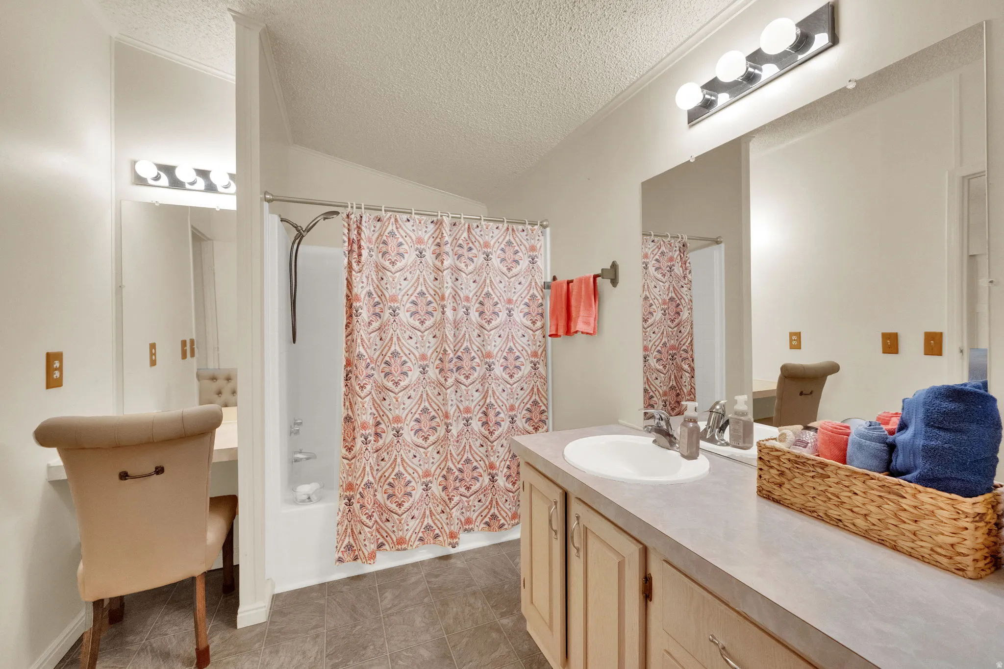 Full bath featuring shower / bathtub combination with curtain, vanity, a textured ceiling, vaulted ceiling, and light tile patterned floors