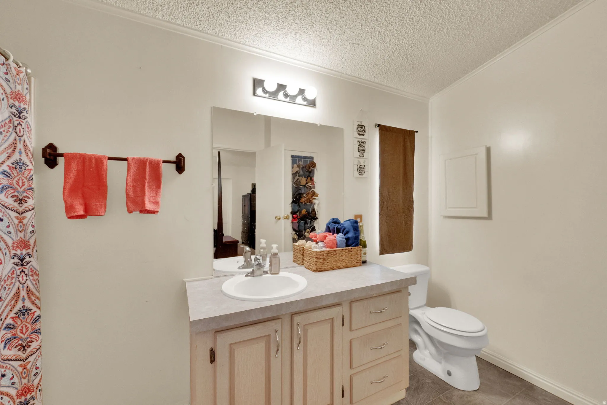 Full bathroom with vanity, a textured ceiling, ornamental molding, light tile patterned floors, and curtained shower