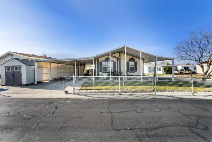 View of front of house featuring a fenced front yard, an attached carport, driveway, and a shed