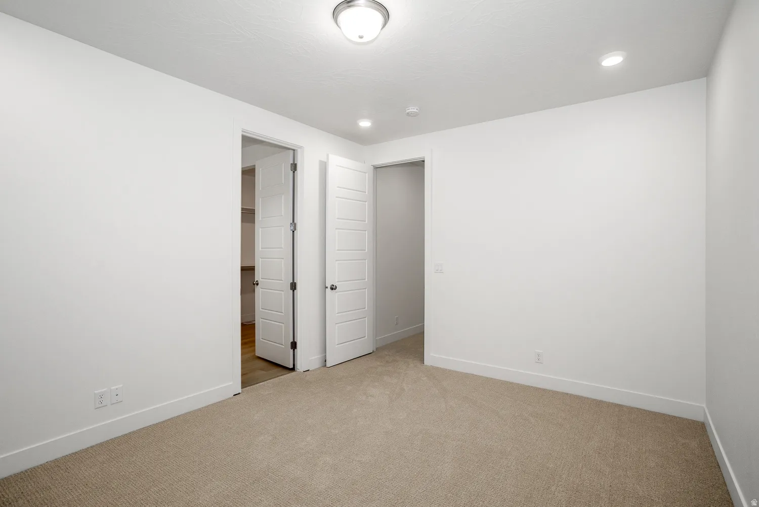 Unfurnished bedroom featuring a spacious closet, light colored carpet, and recessed lighting