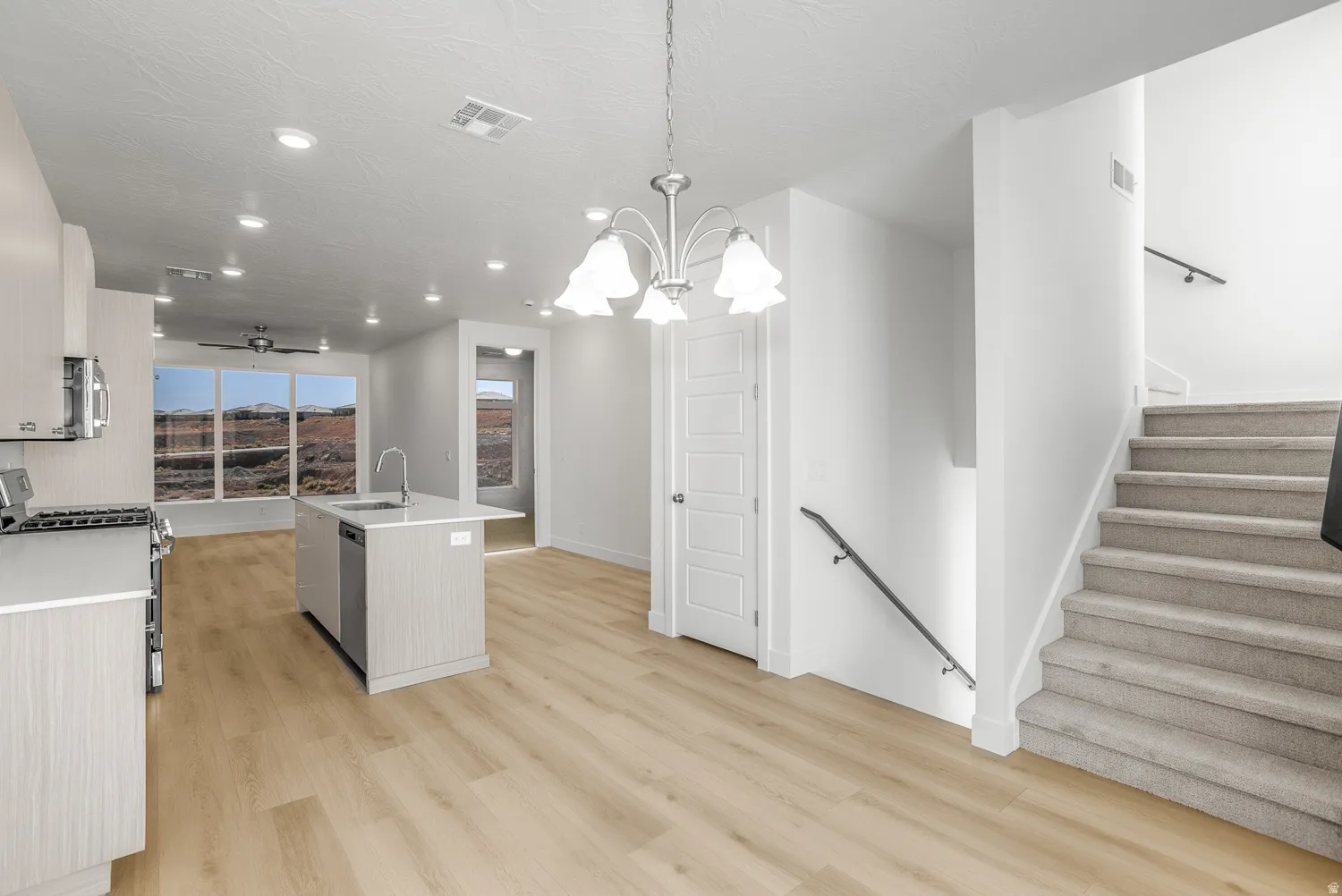 Kitchen featuring appliances with stainless steel finishes, a kitchen island with sink, hanging light fixtures, recessed lighting, and light wood-style floors