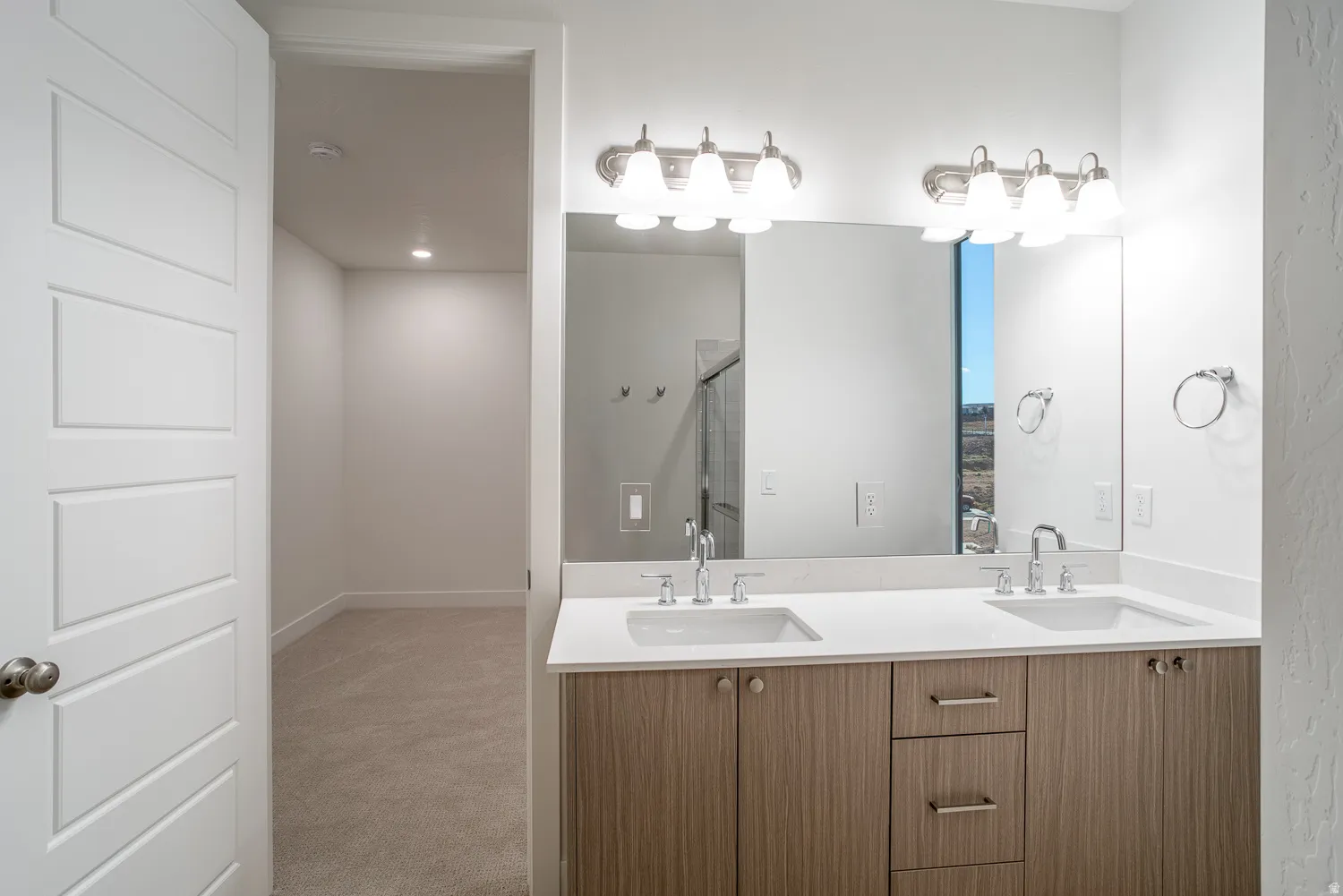 Full bath featuring double vanity, light carpet, and a stall shower