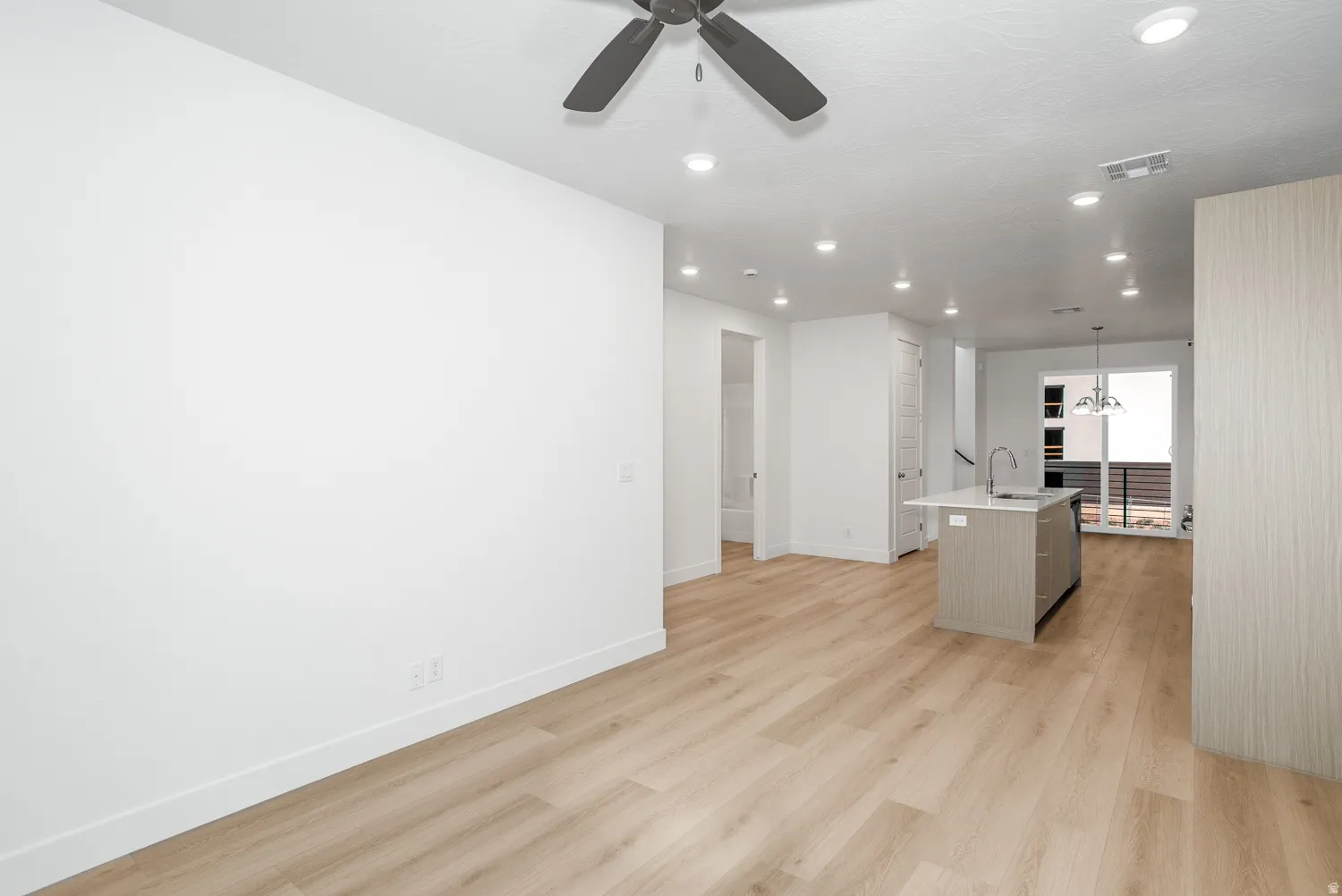 Unfurnished living room with recessed lighting, light wood finished floors, a chandelier, and a ceiling fan
