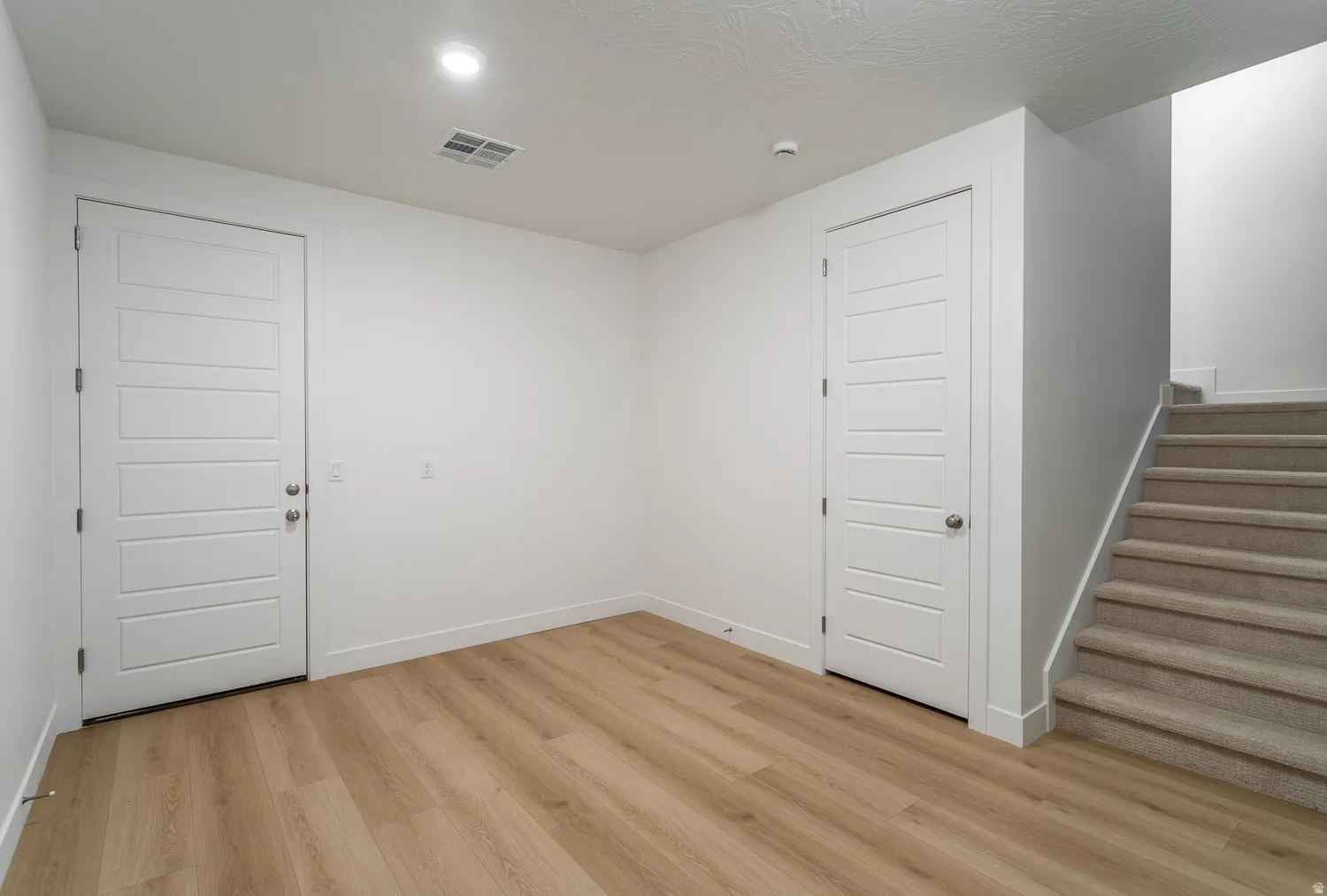 Spare room with stairway and light wood finished floors