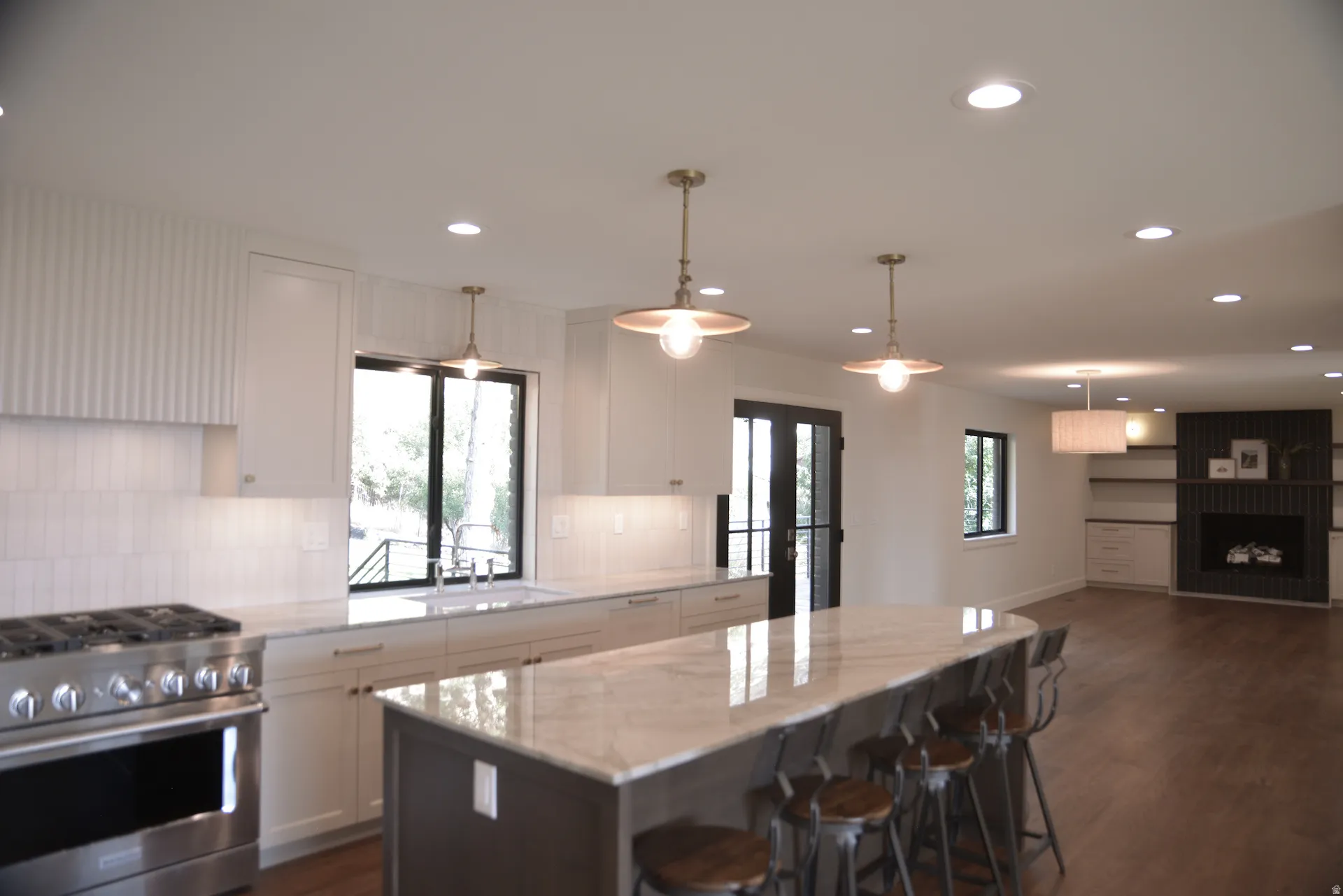 Kitchen with stainless steel gas range oven, white cabinets, decorative backsplash, dark wood finished floors, and recessed lighting