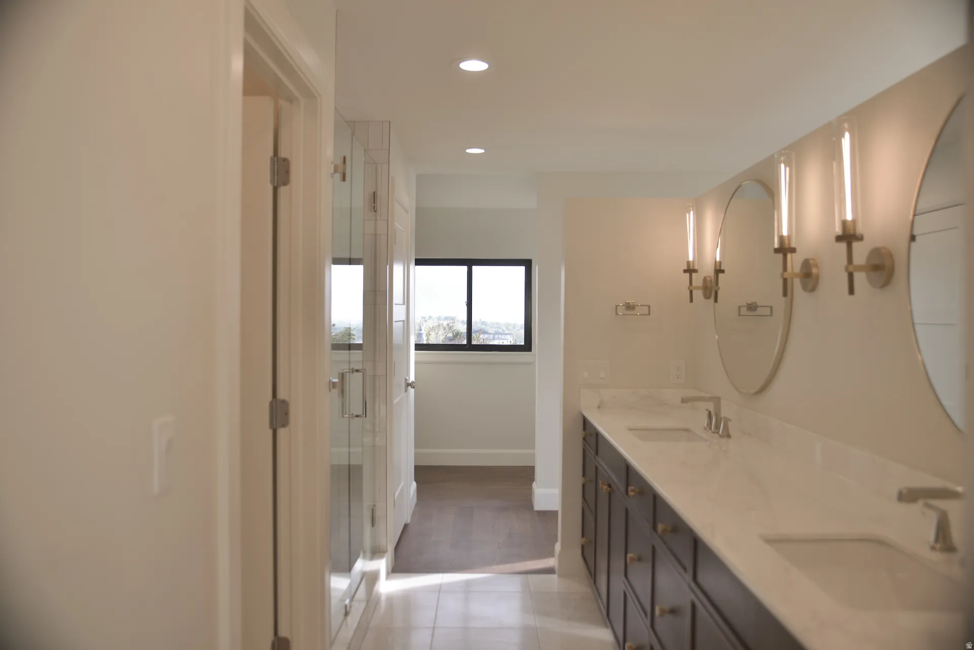 Bathroom featuring double vanity, a shower stall, light tile patterned floors, and recessed lighting