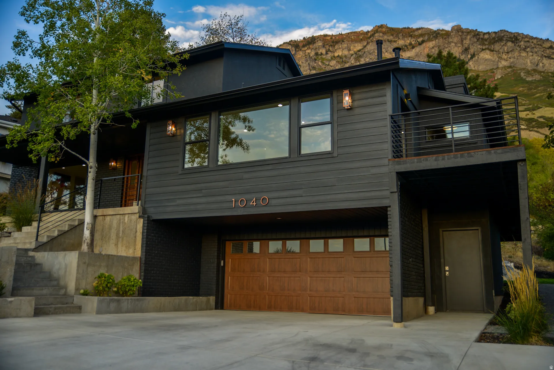 Contemporary home featuring a balcony, brick siding, stairway, and driveway