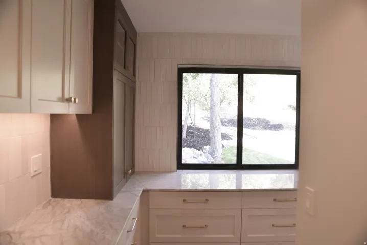 Kitchen with white cabinetry and light stone countertops
