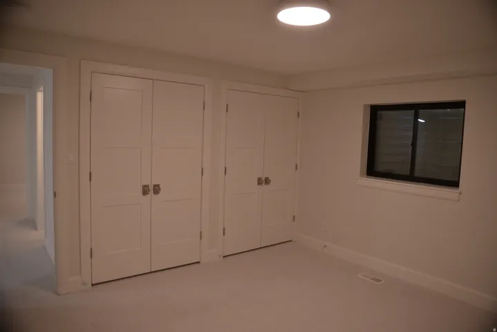 Unfurnished bedroom featuring light colored carpet and multiple closets