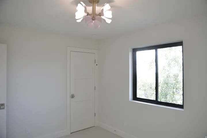 Unfurnished room featuring a chandelier and baseboards