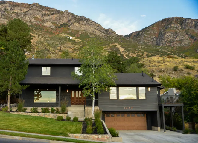 View of front of property with a mountain view, concrete driveway, a garage, a front yard, and a porch