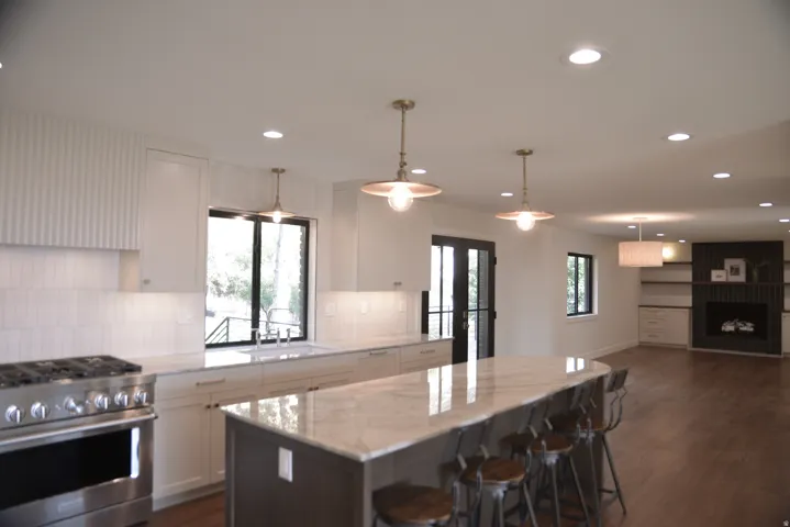 Kitchen with stainless steel gas range oven, white cabinets, decorative backsplash, dark wood finished floors, and recessed lighting