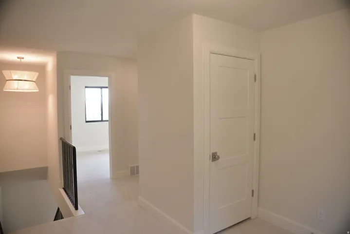 Corridor featuring light carpet and an upstairs landing