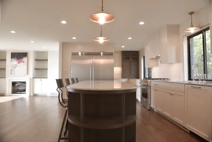 Kitchen featuring high end appliances, white cabinets, glass insert cabinets, plenty of natural light, and recessed lighting