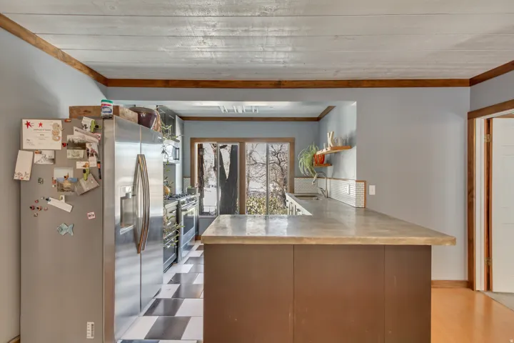 Kitchen featuring appliances with stainless steel finishes, a peninsula, light countertops, light flooring, and ornamental molding
