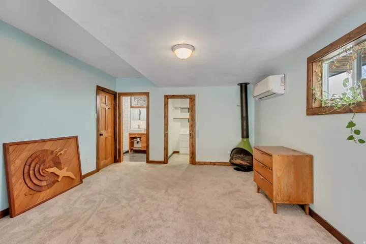 Bedroom featuring a spacious closet, light colored carpet, and a wall unit AC
