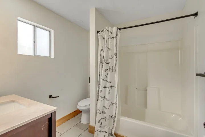 Full bathroom with vanity, light tile patterned floors, and shower / bath combo with shower curtain