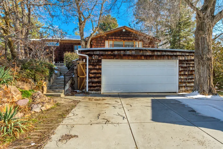 View of front of property with a garage, driveway, and stairs