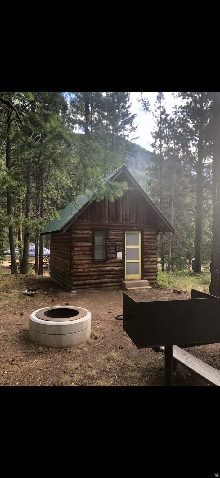 View of home's exterior with log siding and a fire pit