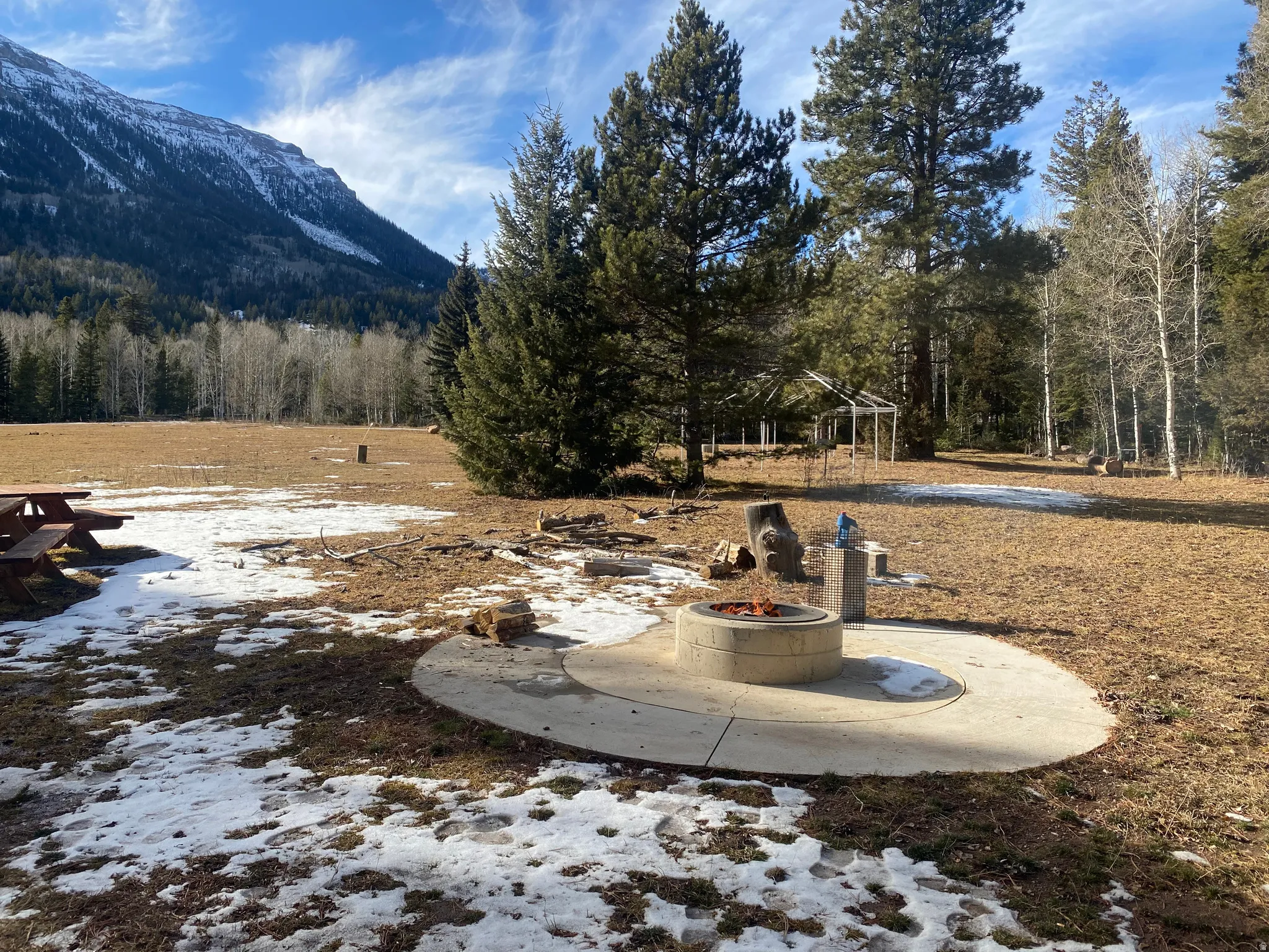 Snowy yard with a patio, an outdoor fire pit, and a mountain view