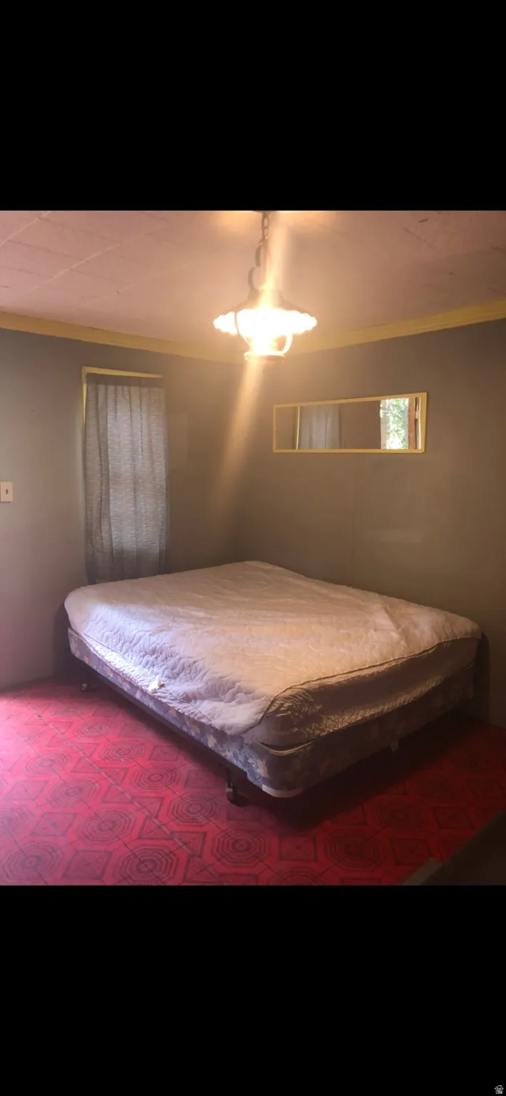 Bedroom with a ceiling fan, crown molding, and dark colored carpet