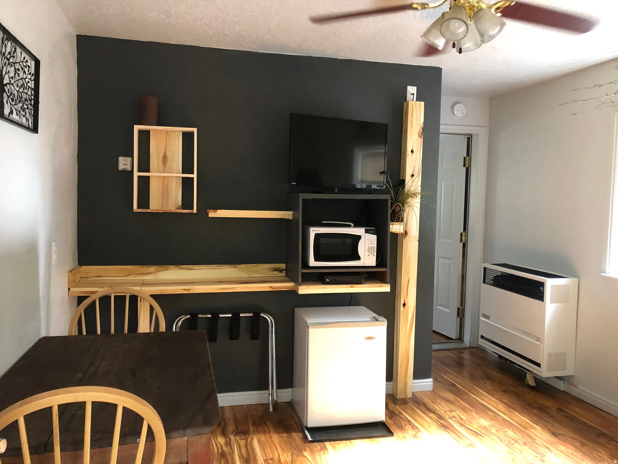 Kitchen featuring white appliances, wood finished floors, ceiling fan, and heating unit