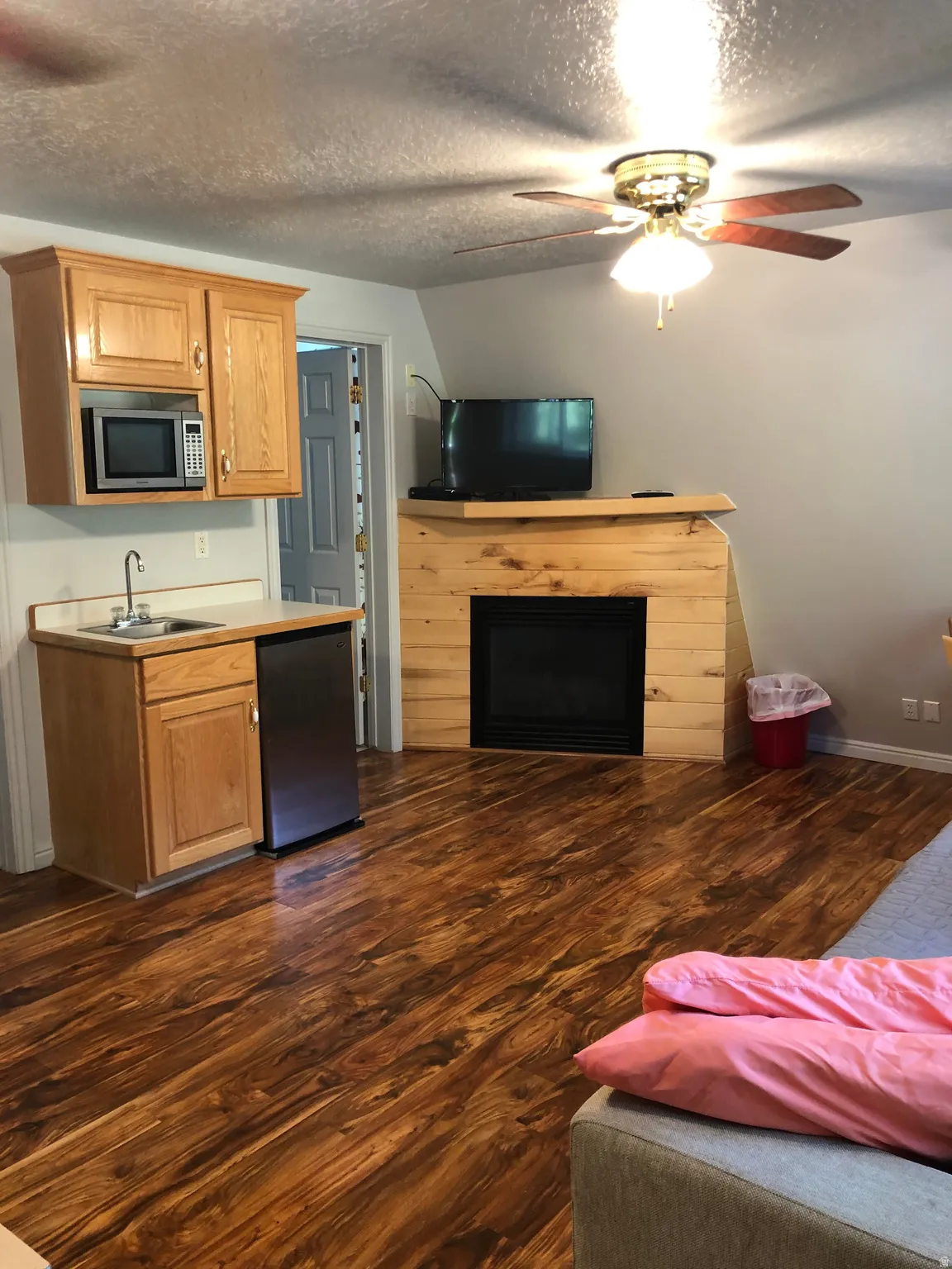 Kitchen with ceiling fan, a textured ceiling, dark wood-type flooring, light countertops, and a fireplace