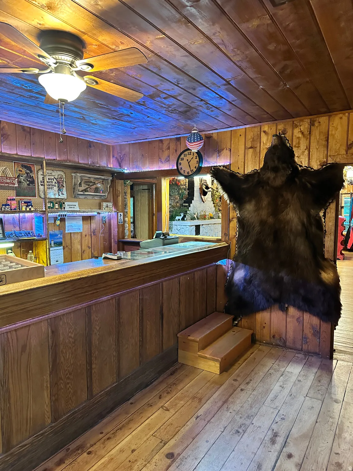 Bar area featuring wood ceiling, wooden walls, light wood finished floors, and ceiling fan