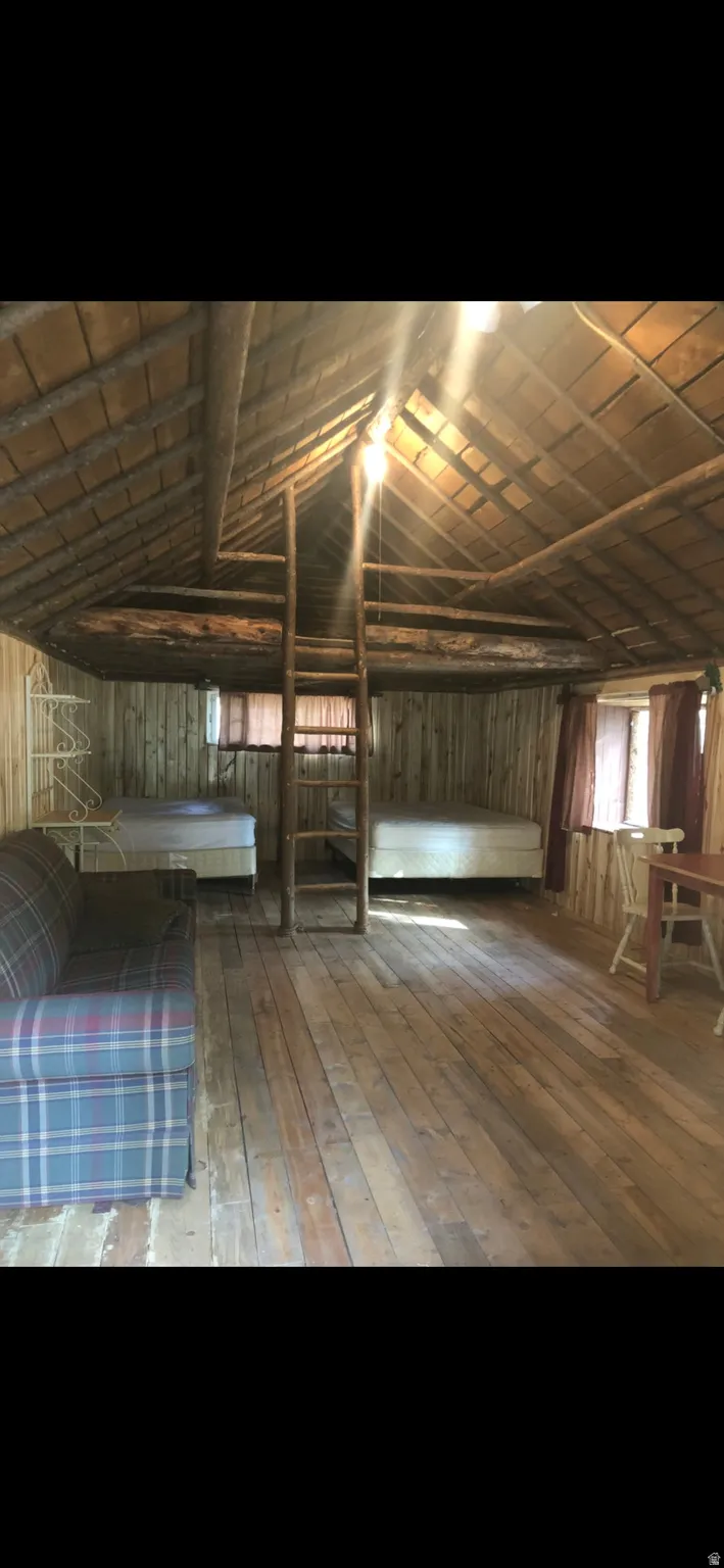 Misc room with wooden walls, lofted ceiling, and hardwood / wood-style floors