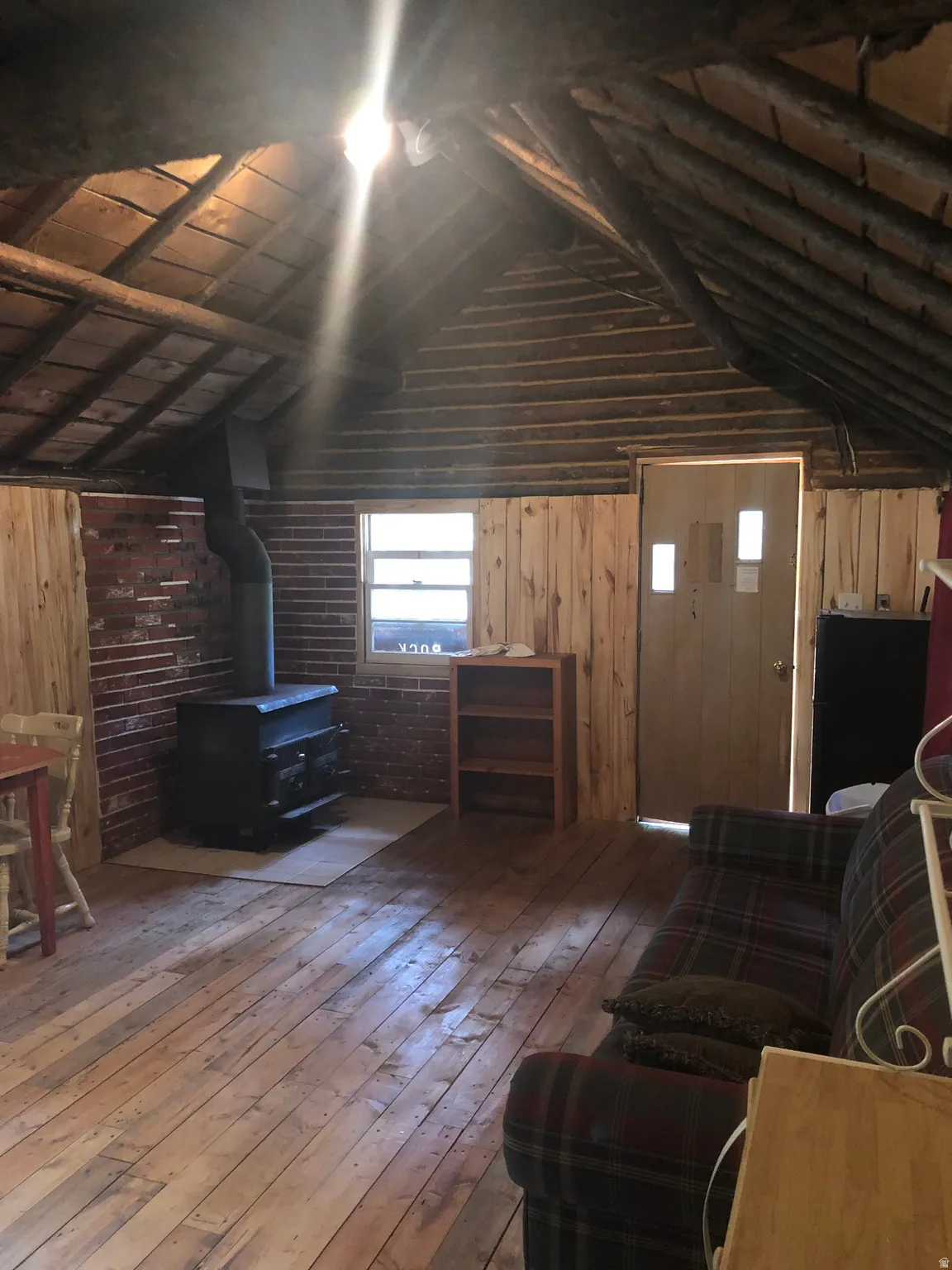 Living room featuring a wood stove, hardwood / wood-style floors, wood walls, and wooden ceiling