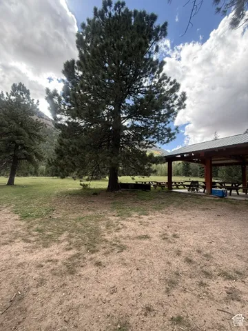 Expansive outdoor space featuring a covered pavilion structure, mature trees, and a flat grass area