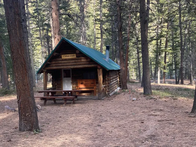 View of front of home with log exterior, an outbuilding, and a metal roof