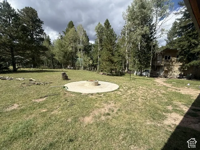 Expansive grassy area featuring a circular paved patio with an integrated fire pit