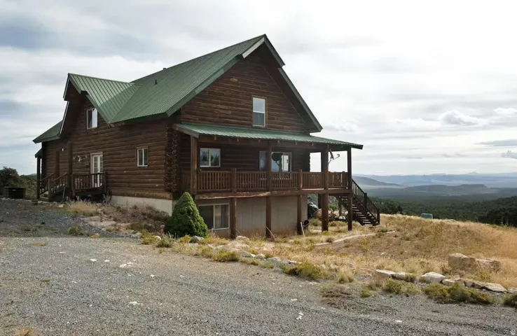 View of home's exterior with stairway, covered porch, a metal roof, and log exterior